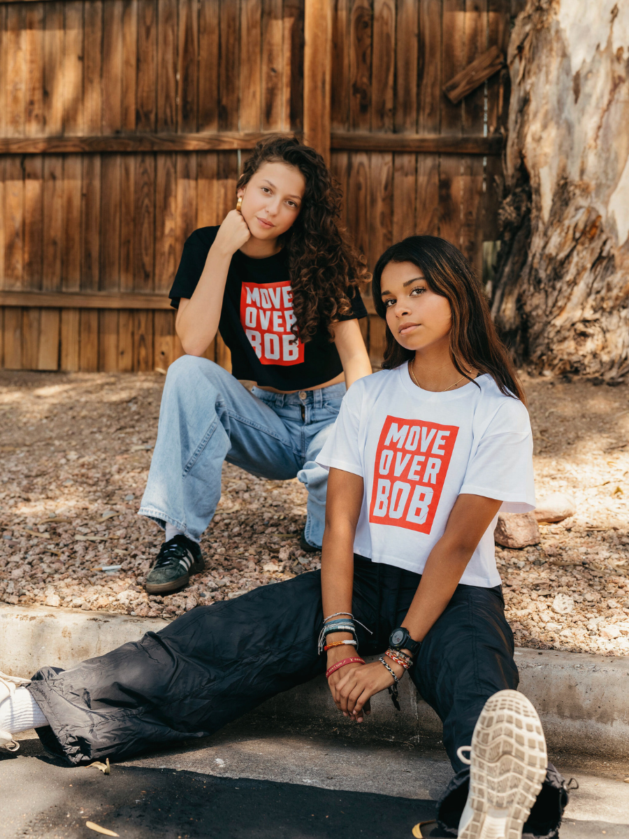 Two people wearing 'Move Over Bob' shirts sitting outdoors.