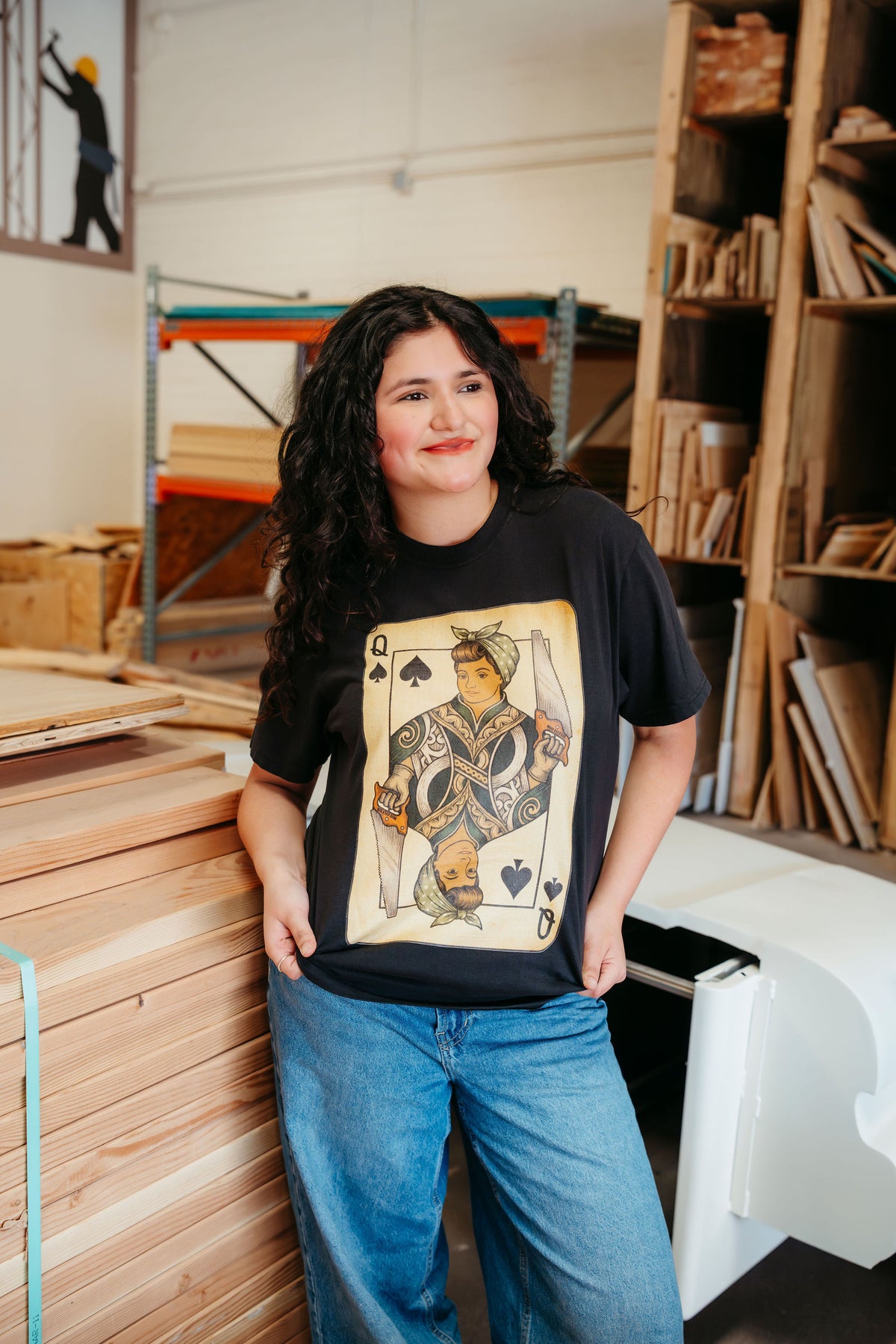 Woman in a wood shop wearing the black Queen of the Cut tee
